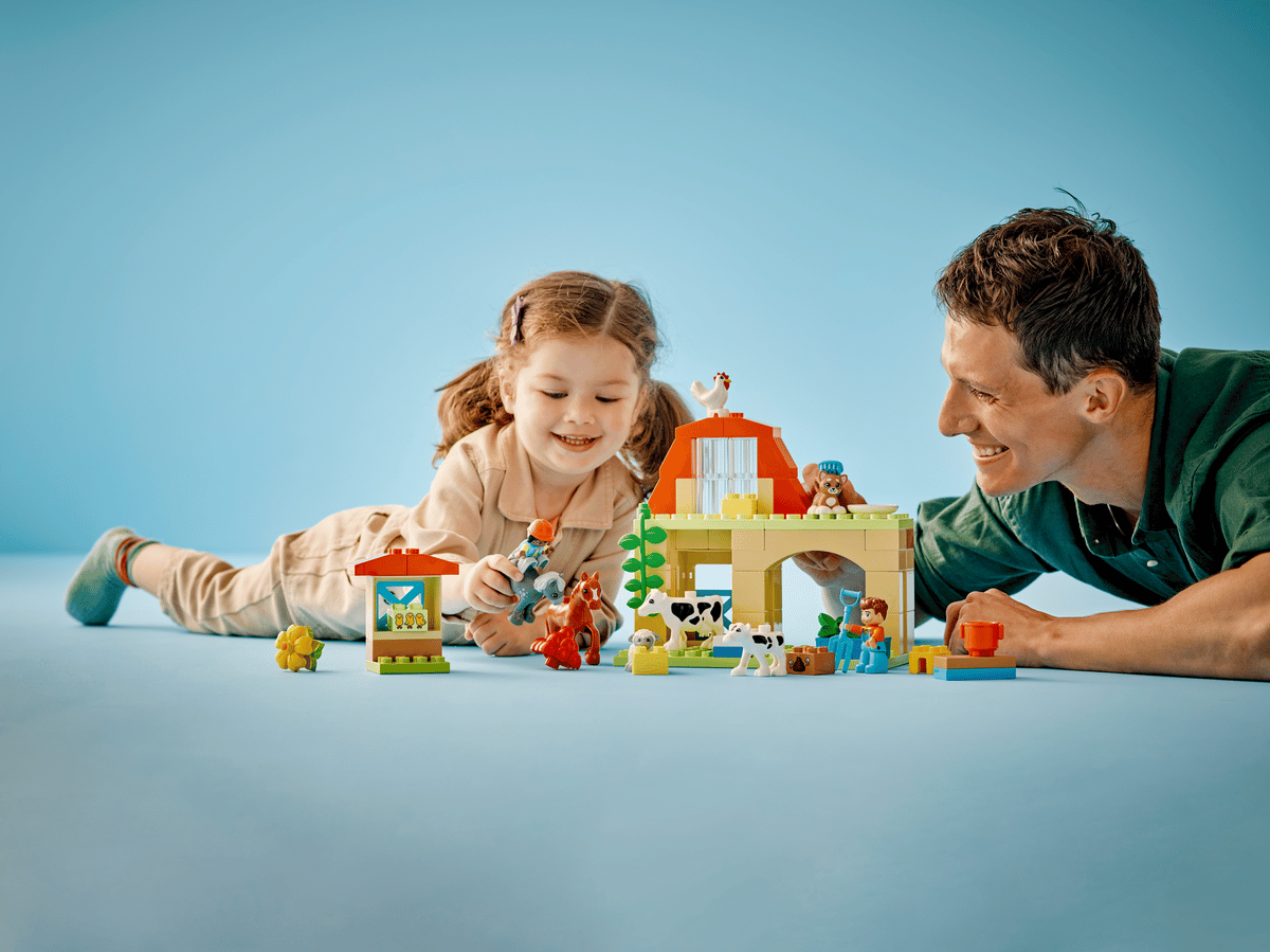 The DUPLO child figure riding the red push along toy tractor accessory piece across the farm